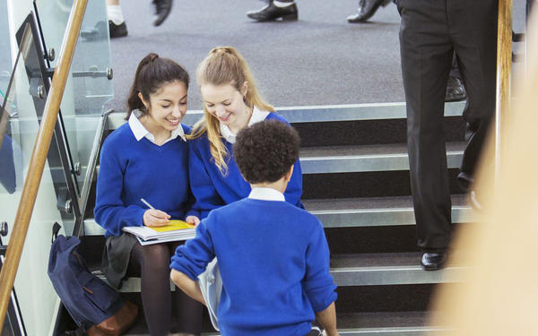 School students working in the school corridor and wearing blue school uniforms.