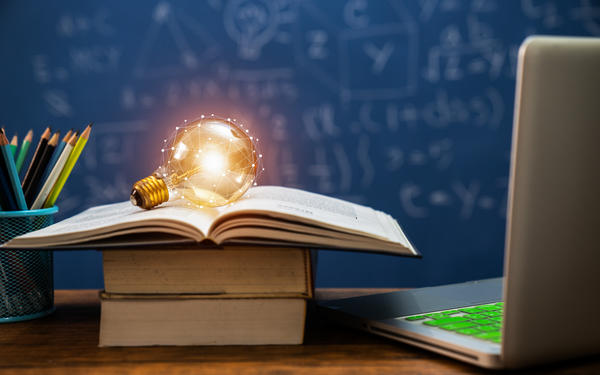 lightbulb on top of books beside a laptop