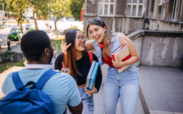 Group of university students chatting outside the teaching building after class