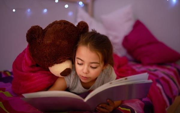 Girl reading book with teddy