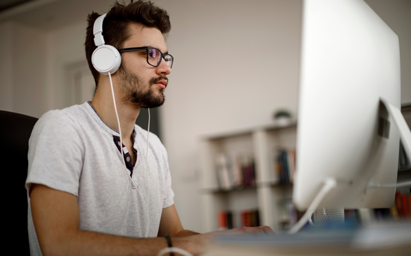 Man looks at screen with headphones on 