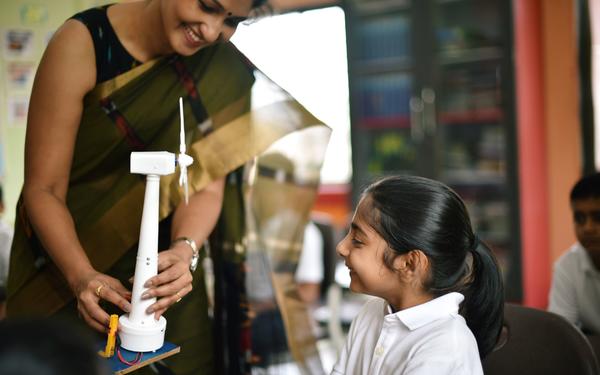 Teacher in India showing a student a model windmill