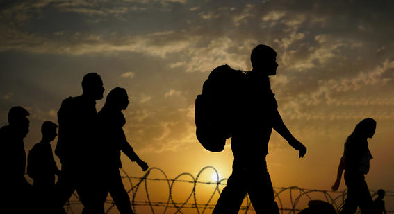 Column of migrants walking to the border in the sunset