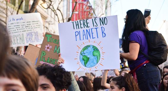 Group of people marching outdoors. One sign reads 'There is no planet B'
